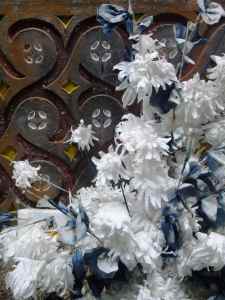 Plastic floral crucifix against traditional wood carvings: Kete Keto, Tana Toraja, Sulawesi, Indonesia.