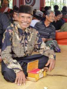 Mourner opens box full of kretek cigarettes in family area at Torajan funeral: Tana Toraja, Sulawesi, Indonesia.