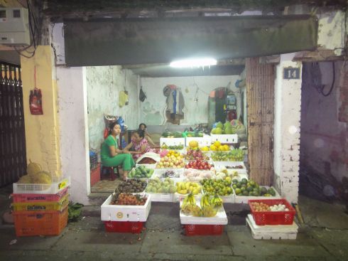 View into fruit store in alleyway, Hanoi, with bananas, eggs, litchis in foreground.