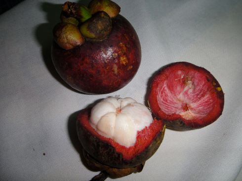 One whole mangosteen, one halved to reveal the fruit.