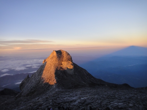 Low's Peak casts a shadow and refracts the sunrise, Mount Kinabalu, Borneo, Malaysia.